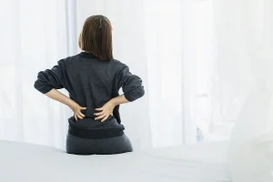 背中の張りを訴えるベッドに座る女性