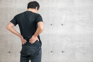 ヘルニアに悩み、腰に手を当てる男性の後ろ姿