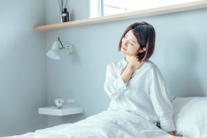 ベッドの上で寝違えを気にしている女性