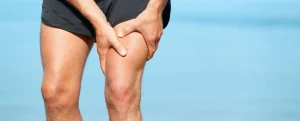 肉離れを起こしてしまい、太ももの表を押さえる男性